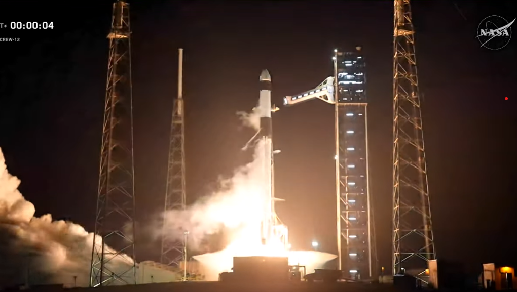 SpaceX Falcon 9 rocket launching Crew-12 mission from Kennedy Space Center at night with bright orange flames and exhaust plume lighting up the launch pad