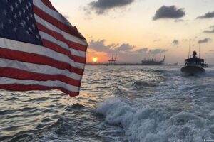 U.S. Navy vessel monitoring an oil tanker in a high-tension maritime zone
